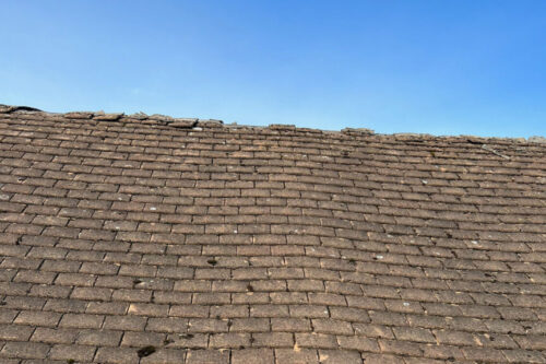 Example of a worn out roof showing damaged, missing tiles and the roof starting to sag